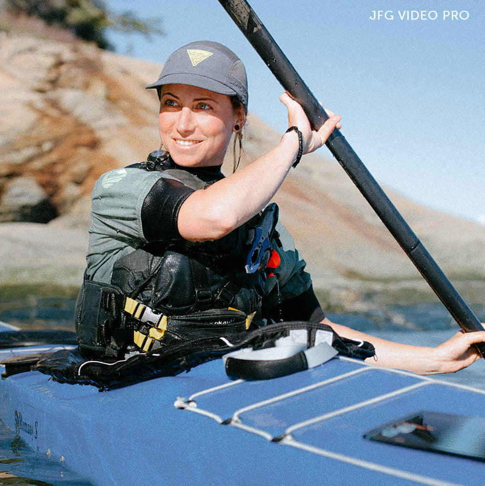 Person kayaking on a calm body of water with rocky terrain in the background